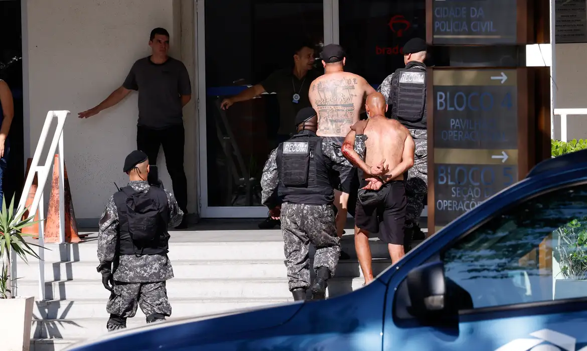 Furto, incêndios e confronto com PM foram registrados na orla carioca Mais de 200 torcedores do Peñarol foram presos nesta quarta-feira (23) na praia do Recreio, zona oeste do Rio de Janeiro, por uma confusão generalizada que teve registros de furto, incêndios e confronto direto com a Polícia Militar (PM). As informações são da própria PM. A torcida do clube uruguaio está na cidade para acompanhar a partida contra o Botafogo, pela Copa Libertadores da América, a ser disputada nesta noite. O jogo é válido pela semifinal da Copa Libertadores da América. Em nota postada nas redes sociais, a PM diz que agentes do Batalhão Especializado em Policiamento em Estádios faziam policiamento preventivo na região, quando foram alertados do furto de celular em um estabelecimento comercial. O aparelho teria sido encontrado com um dos integrantes do grupo. E o caso foi levado para a 16ª Delegacia de Polícia. Ainda segundo a PM, os torcedores do Peñarol iniciaram a confusão com um grupo de pessoas na praia, fizeram saques, depredaram estabelecimentos comerciais e veículos na região. Uma pistola foi apreendida pelos policiais. O governador do Rio, Cláudio Castro, disse, em rede social, que mais de 200 torcedores causaram “confusão generalizada na zona oeste” e foram detidos e levados para a Cidade da Polícia, espaço da Polícia Civil do estado localizado no Jacaré, zona norte, que abriga delegacias especializadas. Segundo o governador, policiais do Batalhão de Choque e do Batalhão de Rondas Especiais foram enviados para reforçar a segurança no Recreio. “O Rio não é lugar de baderna. Determinei que as polícias prendam, levem para a delegacia e escoltem para fora do Rio de Janeiro os torcedores do Peñarol, que causaram uma confusão generalizada na zona oeste. Já estamos levando para a Cidade da Polícia mais de 200 detidos”, escreveu o governador. O Centro de Operações da Prefeitura do Rio confirmou que um ônibus foi incendiado na Avenida Lúcio Costa, no Recreio, e que bombeiros foram ao local para controlar o fogo. Sobre a ocorrência, o prefeito Eduardo Paes lembrou ter alertado, algumas vezes, a Polícia Militar que "o local e o modelo trariam esses problemas”. Durante a confusão na praia, o jogador Varela, que é uruguaio e atua no Flamengo, foi visto conversando com torcedores do Peñarol no local. O clube se manifestou sobre vídeos que circulam nas redes sociais e mostram a presença de Varela na praia. "O lateral recebeu a ligação de dois amigos e foi retirá-los da confusão formada na Praia do Recreio. O jogador está a caminho de uma confraternização com elenco e comissão técnica. O assunto está entregue ao VP de futebol, Marcos Braz”, diz nota oficial do clube postada nas redes sociais. Torcedores do Peñarol presos na praia do Recreio, zona oeste do Rio de Janeiro, por uma confusão generalizada, chegam na Cidade da Polícia, zona norte da cidade. Foto: Tânia Rêgo/Agência Brasil O próprio atleta pediu desculpas e chamou tudo de "mal-entendido": “Estive na Praia do Recreio para resgatar dois amigos que estavam assustados com a confusão. Não participei de nenhum ato de violência. Perdemos contato assim que cheguei ao local. Esperei por 15 minutos e fui abordado por policiais militares que faziam o seu trabalho. Após tudo ser resolvido, me encaminhei para um almoço com os meus companheiros e comissão técnica. Já conversei com o vice-presidente de futebol, Marcos Braz. Peço desculpas pelo mal-entendido e reafirmo o meu compromisso de levar o Flamengo aos títulos!”, escreveu Varela. A reportagem da Agência Brasil entrou em contato com as assessorias do Club Atlético Peñarol e da Confederação Sul-Americana de Futebol (Conmebol), mas, até o momento, não teve resposta. Ontem (23), o Peñarol havia divulgado recomendações para os torcedores uruguaios que viriam ao país. A nota dizia que reuniões de segurança foram feitas com as autoridades locais e que o ponto de encontro para todos seria na Praia do Pontal, no Recreio. Também diz que a polícia brasileira comunicou que “qualquer torcedor que seja identificado causando desordens” seria “detido imediatamente e deveria pagar o custo dos danos”. O pedido do clube foi para que os torcedores uruguaios tomassem precauções para cuidar de si mesmos e também do clube.